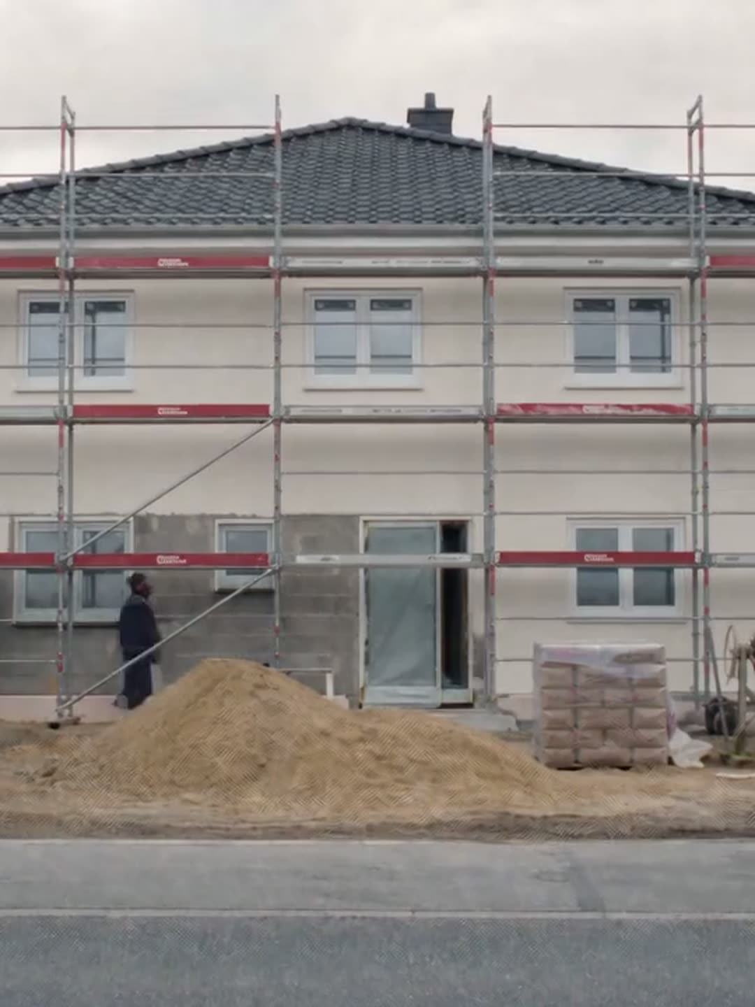 Handwerker ziehen den Putz auf die Fassade, halb graue, halb weiße Wand