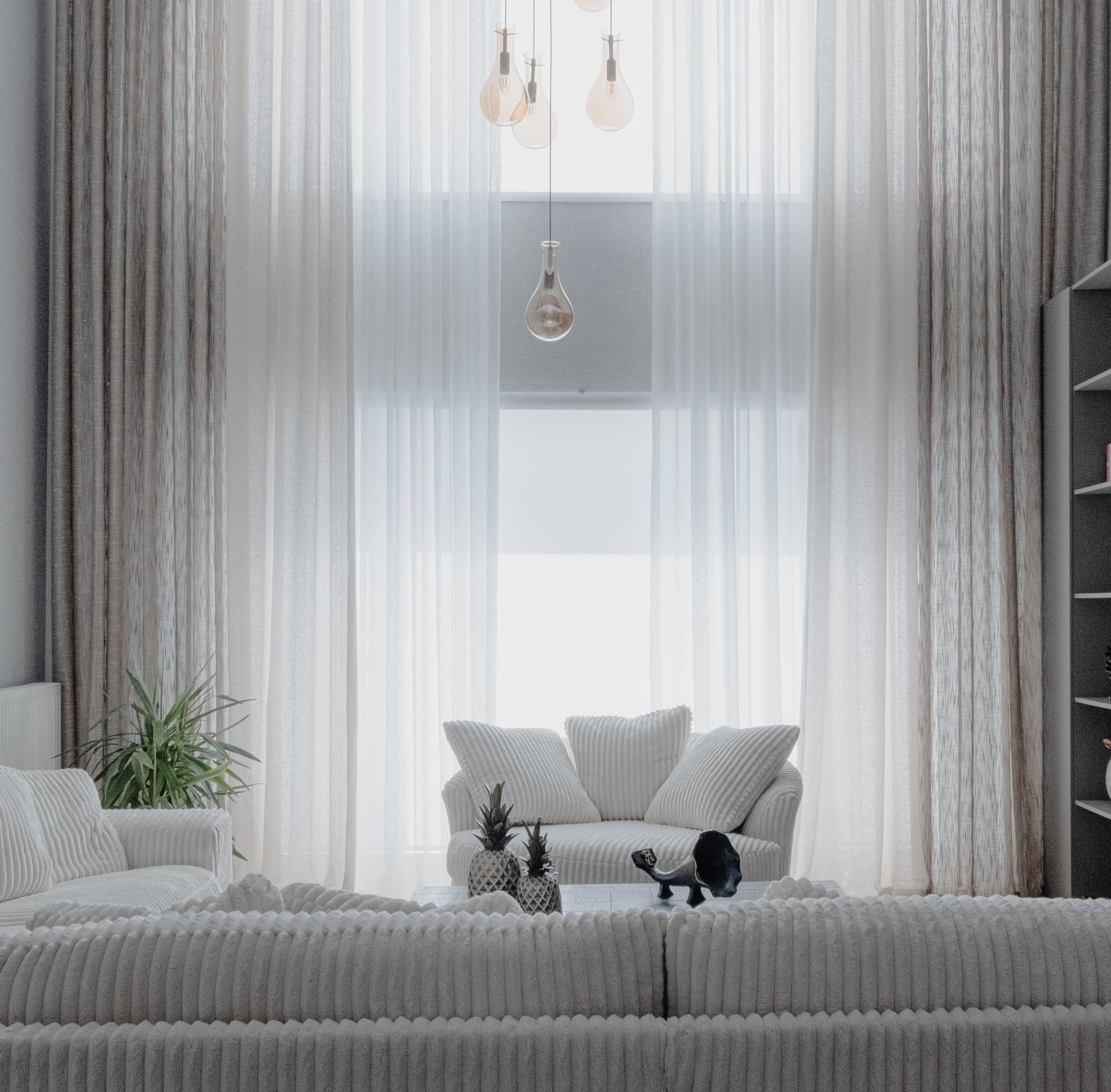 Helles Wohnzimmer mit hellen Polstermöbeln vor einem bodentiefen Fenster.